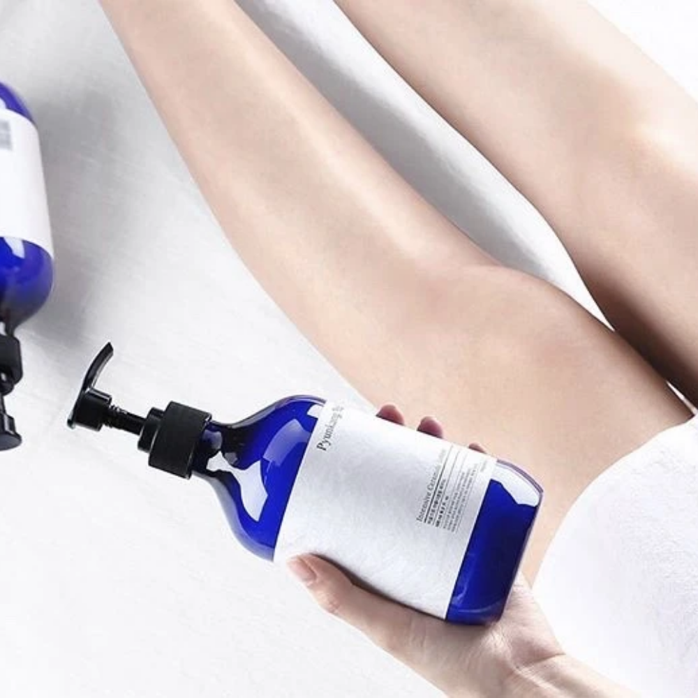 Nainen, joka pitää pulloa Pyunkang Yul Intensive Ceramide Lotion 500ml jalkojensa vieressä.