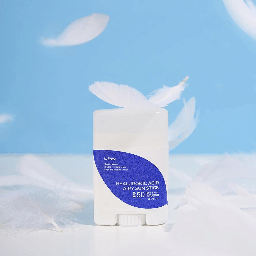 Yksi Isntree Hyaluronic Acid Airy Sun Stick ja SPF 50+ ja hyaluronihappo, koristeltu valkoisilla höyhenillä.