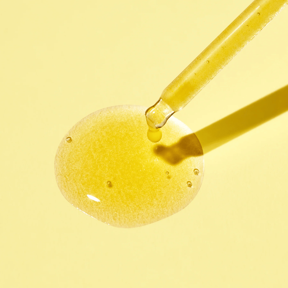 Pisara nestettä keltaisella taustalla, jossa on MISSHAn Vita C Plus Spot Correcting & Firming Ampoule.